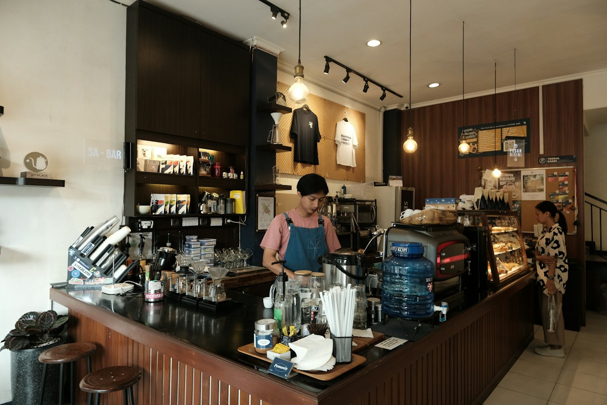 Barista preparing drinks behind a café counter while a customer waits