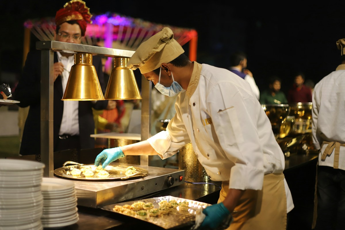 Chef in uniform serving food at an outdoor catered event