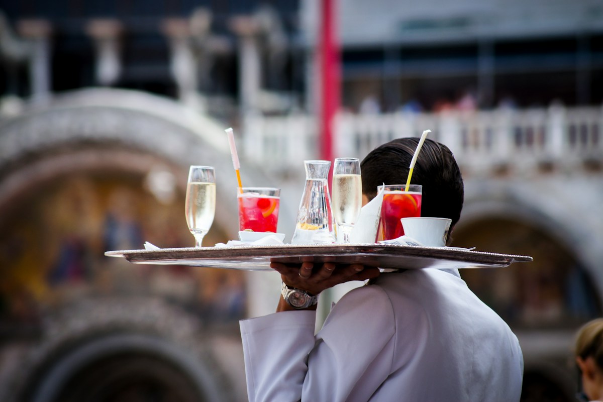Waiter carrying a tray of drinks across an outdoor restaurant terrace